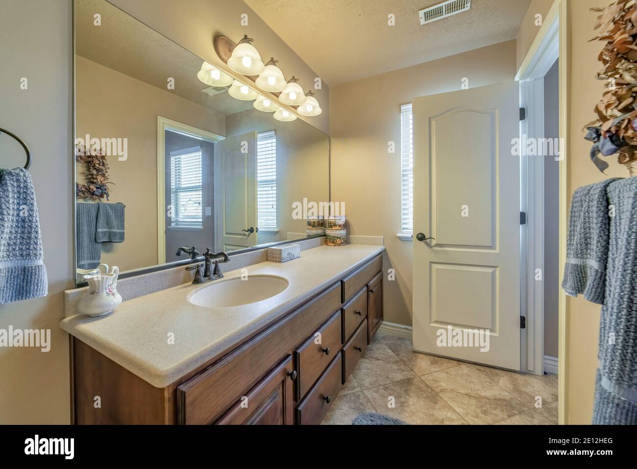 Vanity unit with single oval sink on white countertop over brown wood