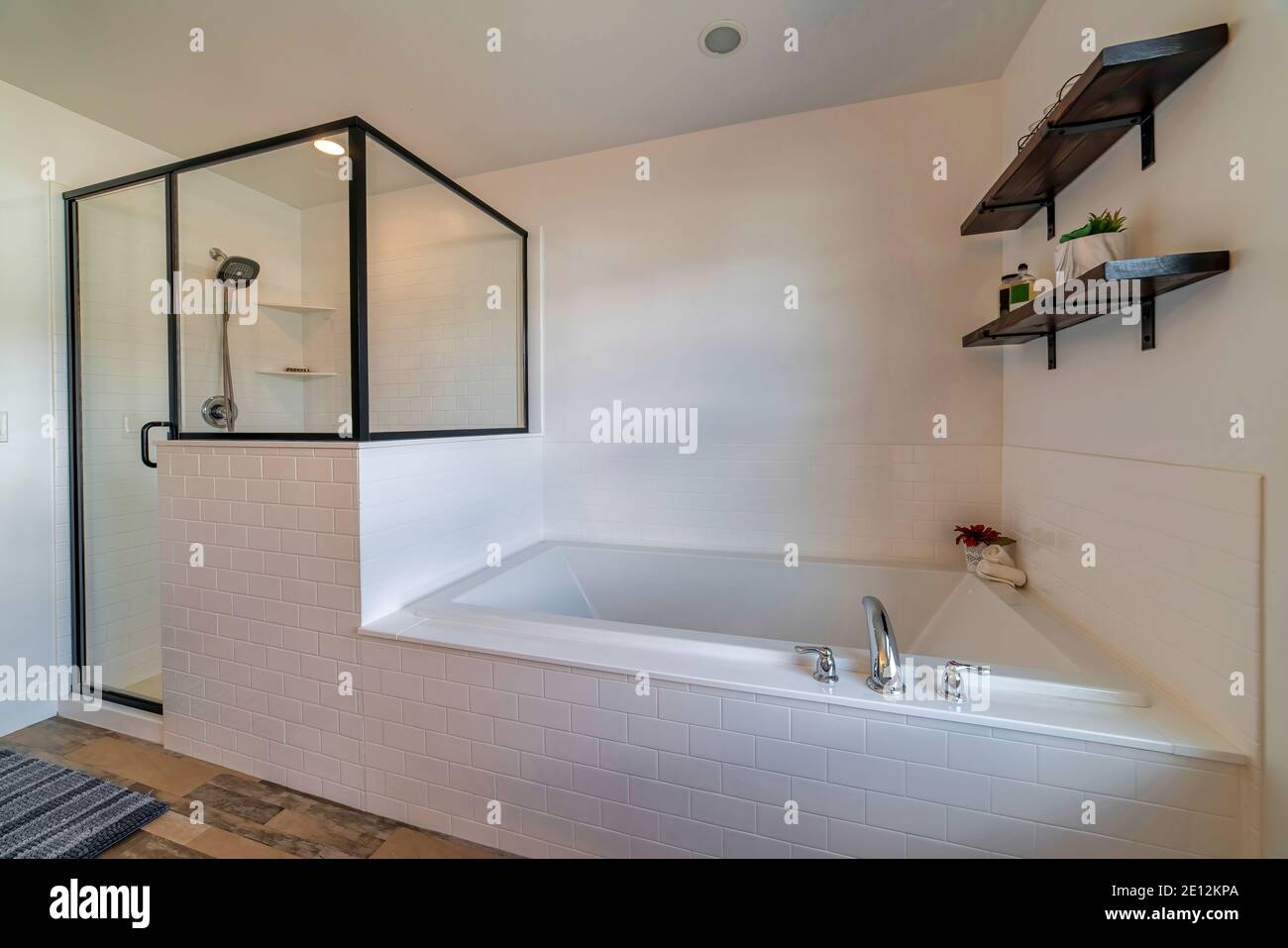 Built in bathtub and glass shower stall against white wall of clean ...