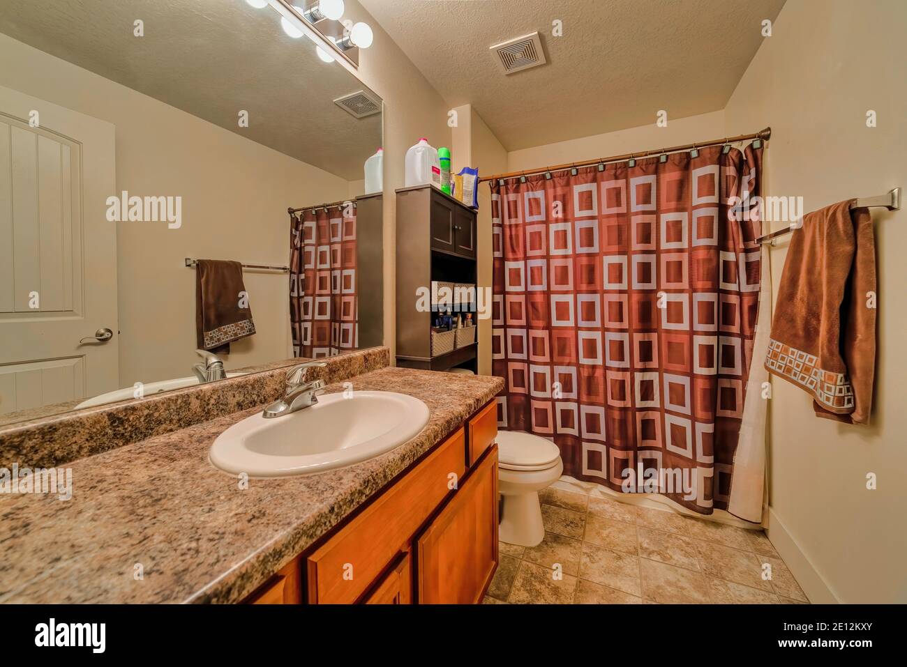 White sink on marble countertop with wood cabinet beside toilet of ...