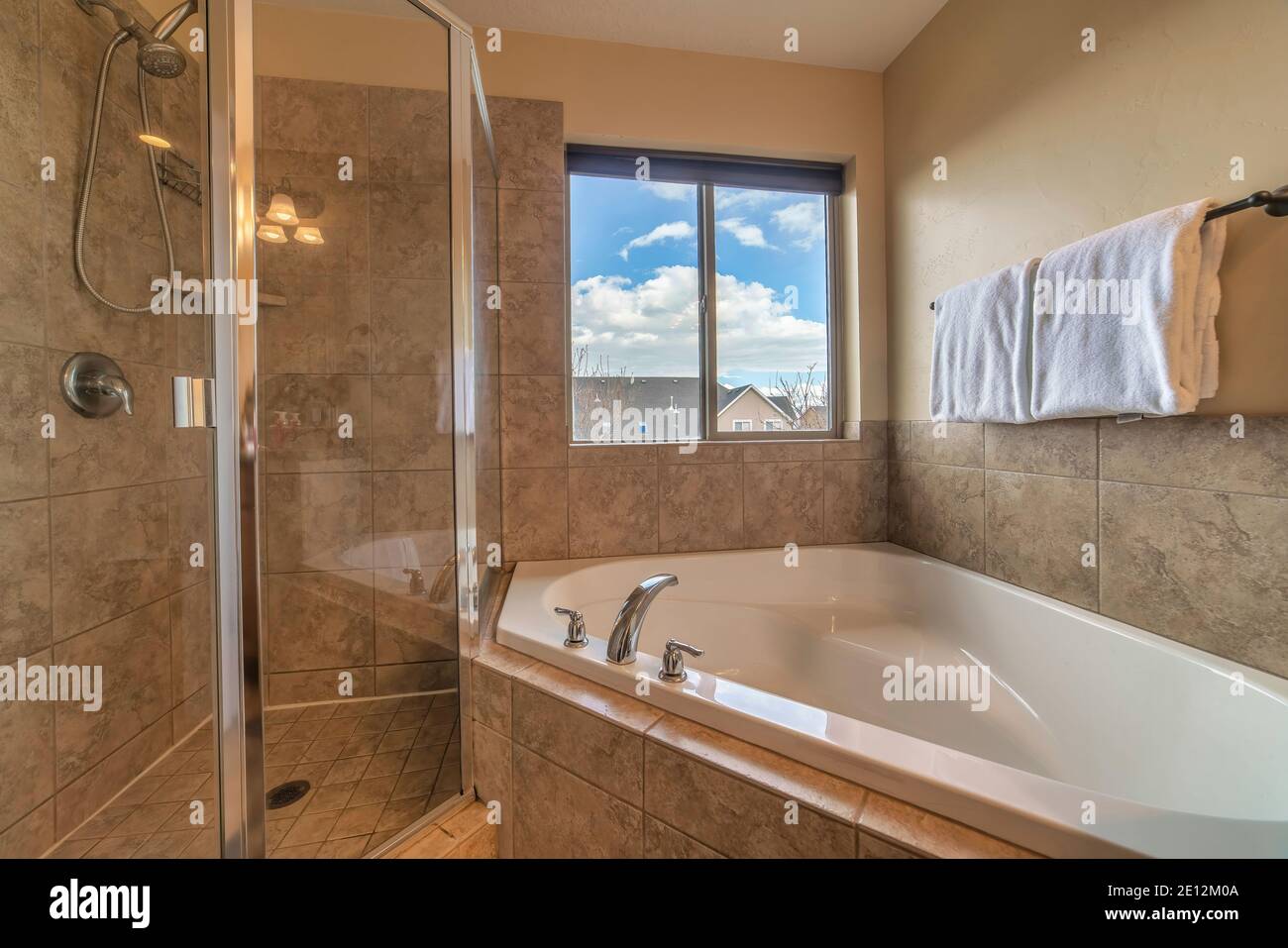 Built in bathtub and shower stall inside bathroom with tiled floor and