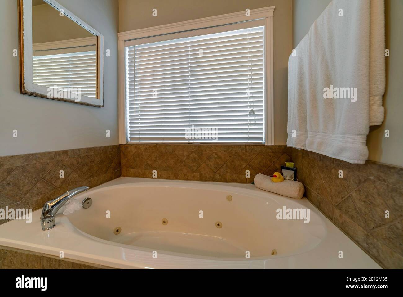 Clean bathtub inside a bathroom with warm toned tiles and white paint