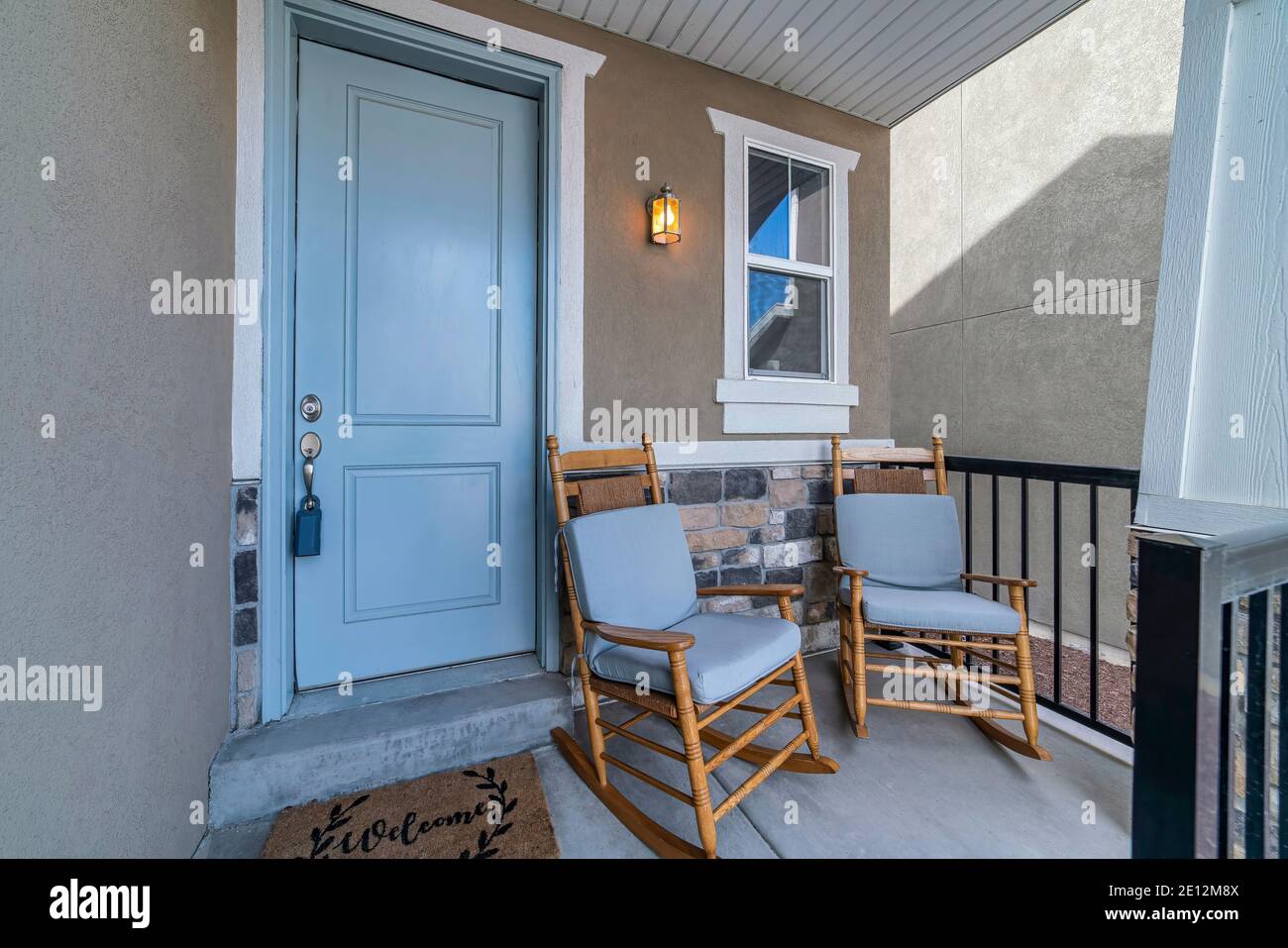 Rocking chairs on the small porch against white front door and window of house Stock Photo