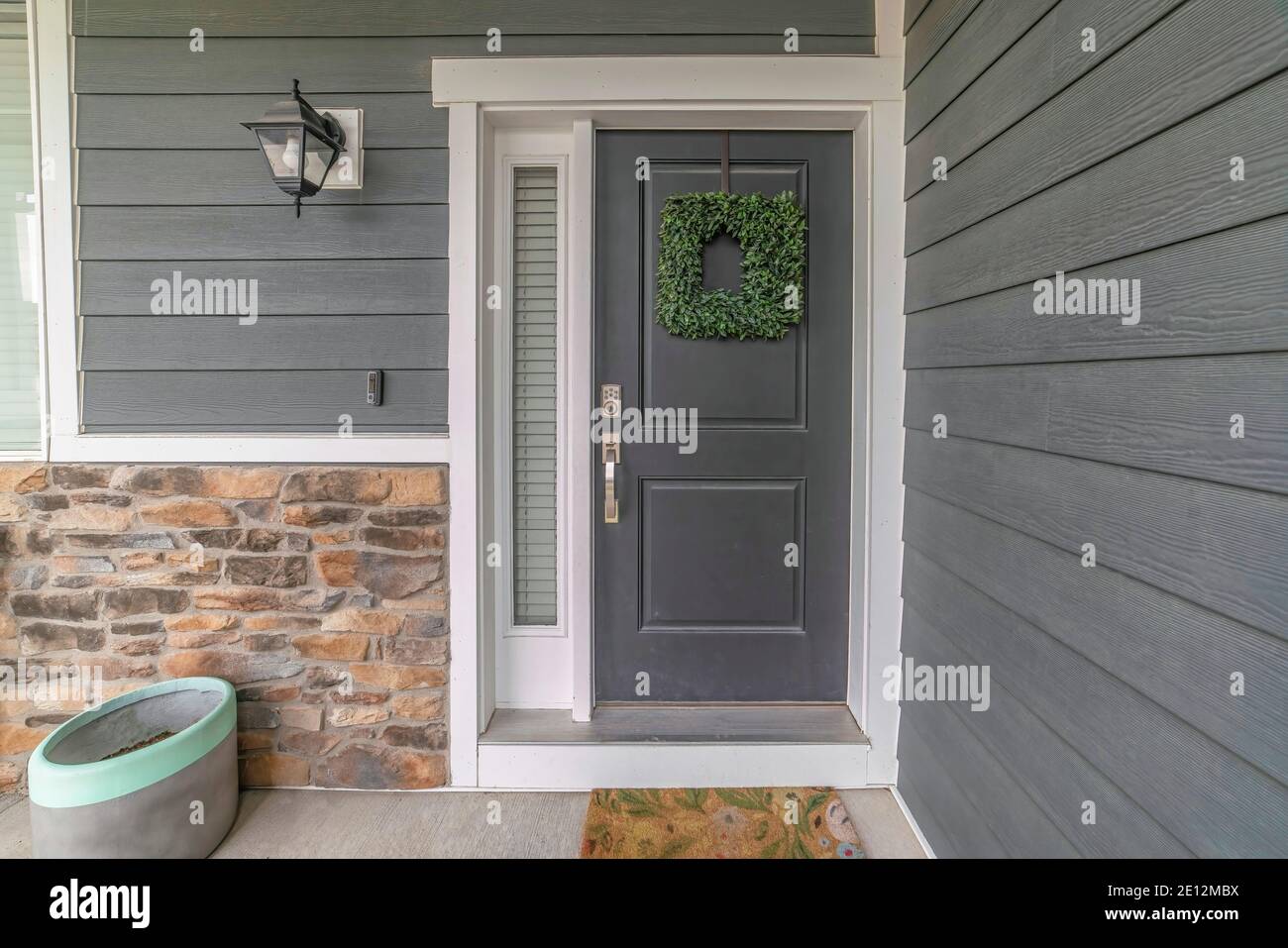 Entrance to a house with side light and gray front door decorated with  wreath Stock Photo - Alamy