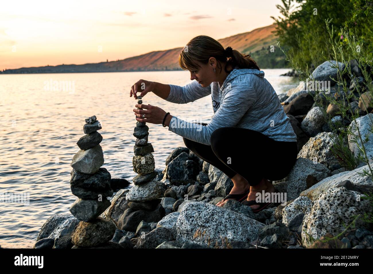 Woman building a cairn along the east shore of Wallowa Lake Stock Photo