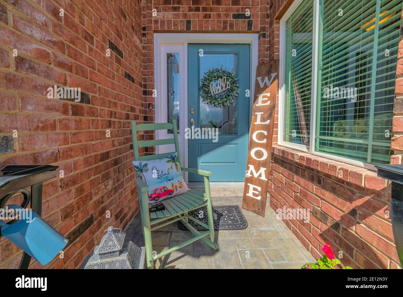 Porch of home with rocking chairs and welcome signboard against blue front door Stock Photo