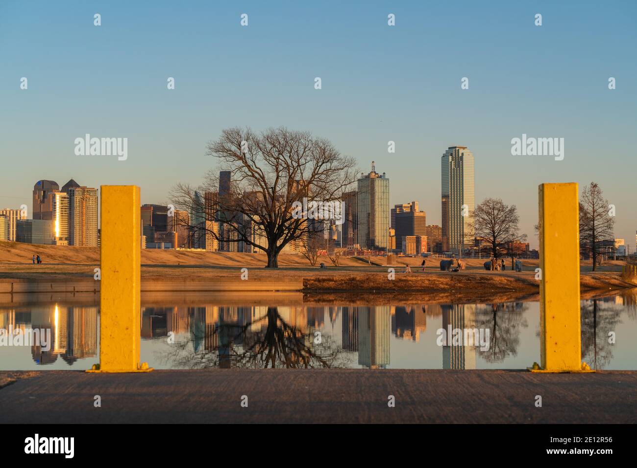 People relaxing at Trammell Crow Park with a view of the Dallas, Texas skyline in the background and reflecting pond in the foreground. Stock Photo