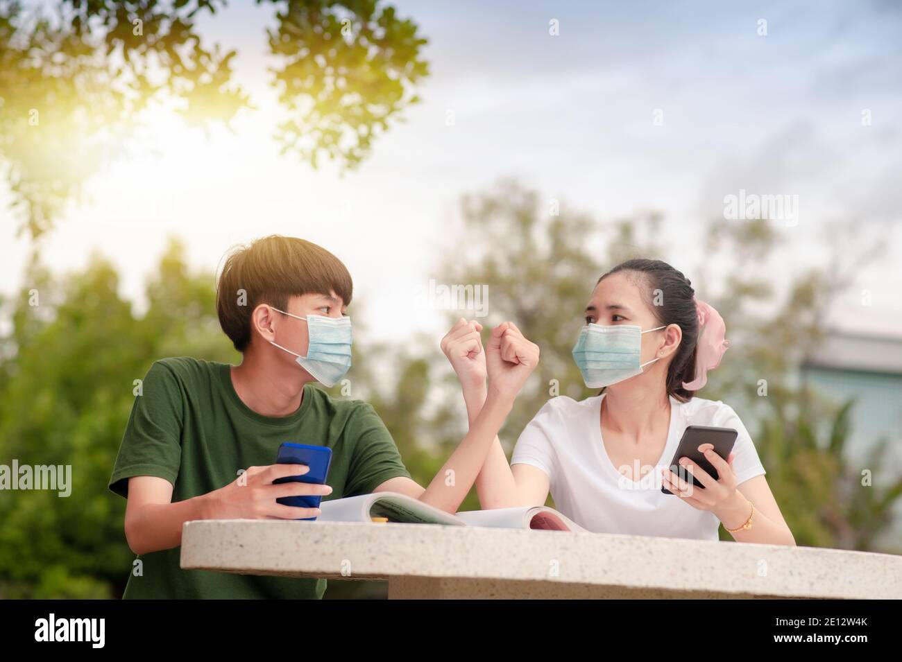 Boy and Girl in face mask new normal shake hand elbow keep social distancing protect coronavirus covid 19 Stock Photo