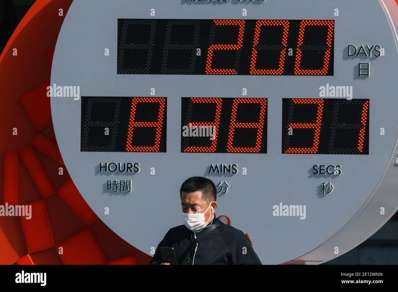 Pedestrian wearing protective facial masks walks by a Tokyo 2020 Olympic official clock indicating 200 days to go on January 04, 2020 in Tokyo Japan. Tokyo, JAPAN 4 January 2021. January 04, 2021 Credit: Nicolas Datiche/AFLO/Alamy Live News Stock Photo