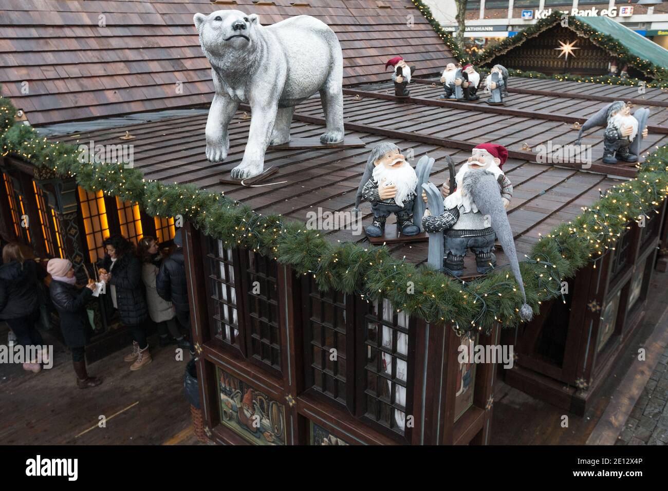 A polar bear and gnomes watch over people drinking gluhwein or mulled wine the Christmas Market, or Weihnachtsmarkt in the historic Altstadt, or in th Stock Photo