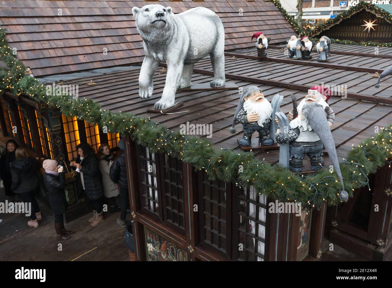 A polar bear and gnomes watch over people drinking gluhwein or mulled wine the Christmas Market, or Weihnachtsmarkt in the historic Altstadt, or in th Stock Photo