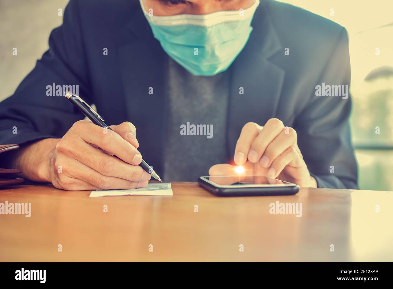 Close up businessman using mobile smartphone to working online and writing short note Stock Photo