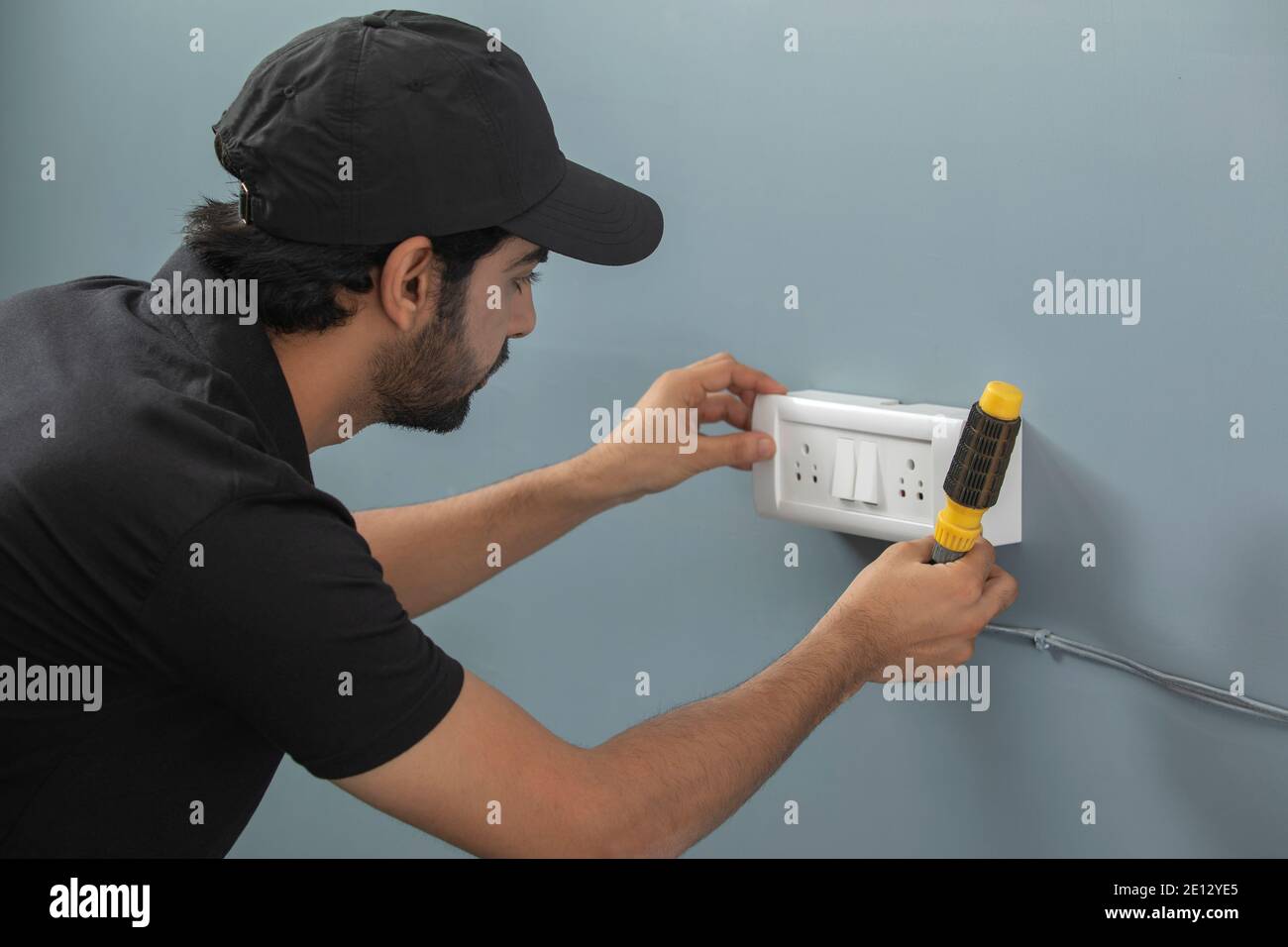 AN ELECTRICIAN REPAIRING SWITCH BOARD WITH EQUIPMENTS Stock Photo