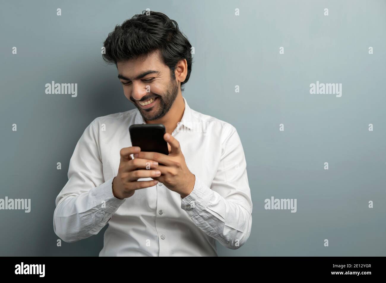 A YOUNG EXECUTIVE LAUGHING WHILE USING MOBILE PHONE DURING VIDEO CONFERENCING Stock Photo
