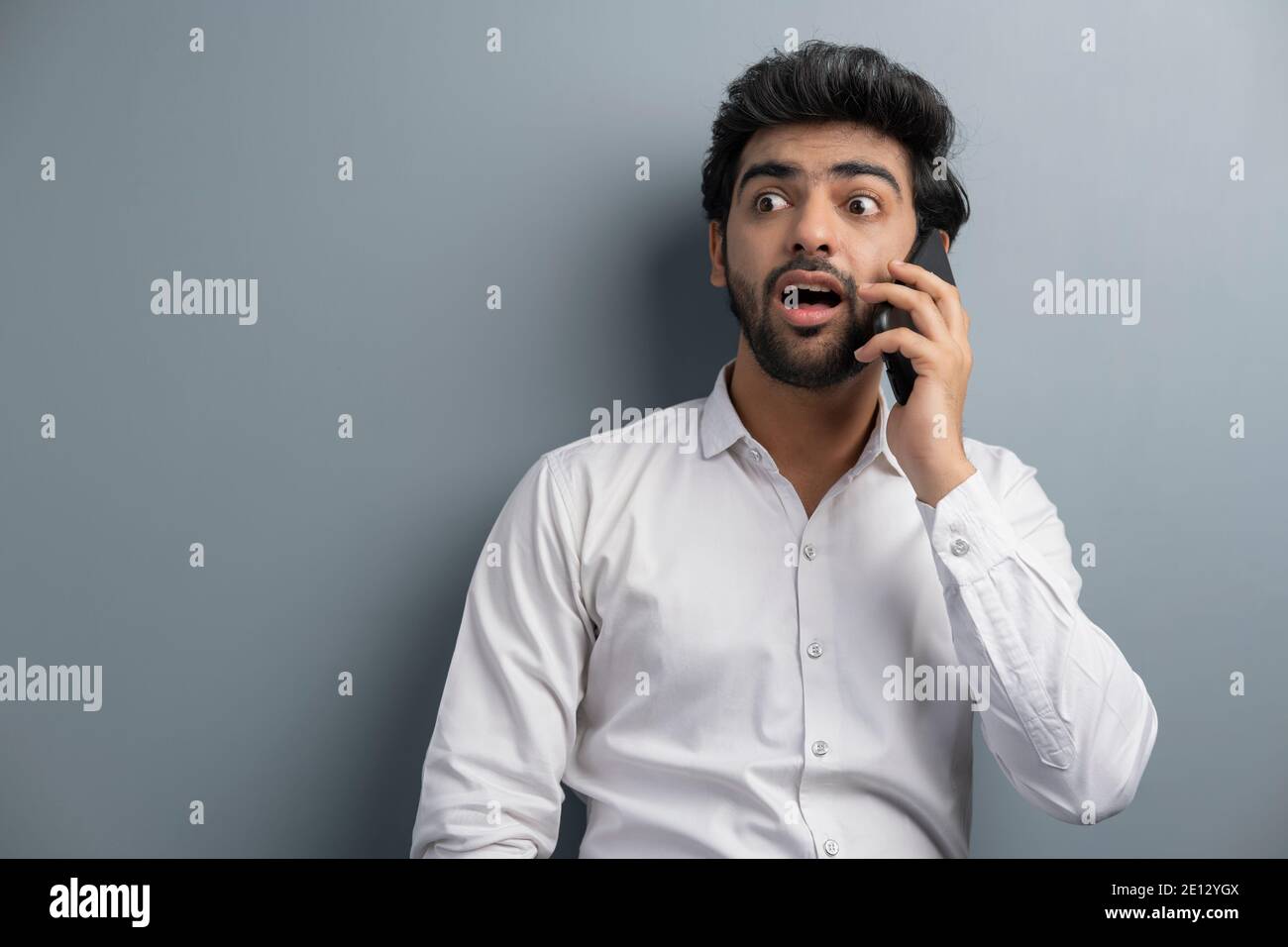 A YOUNG EXECUTIVE LOOKING SURPRISED ON A PHONE CALL Stock Photo