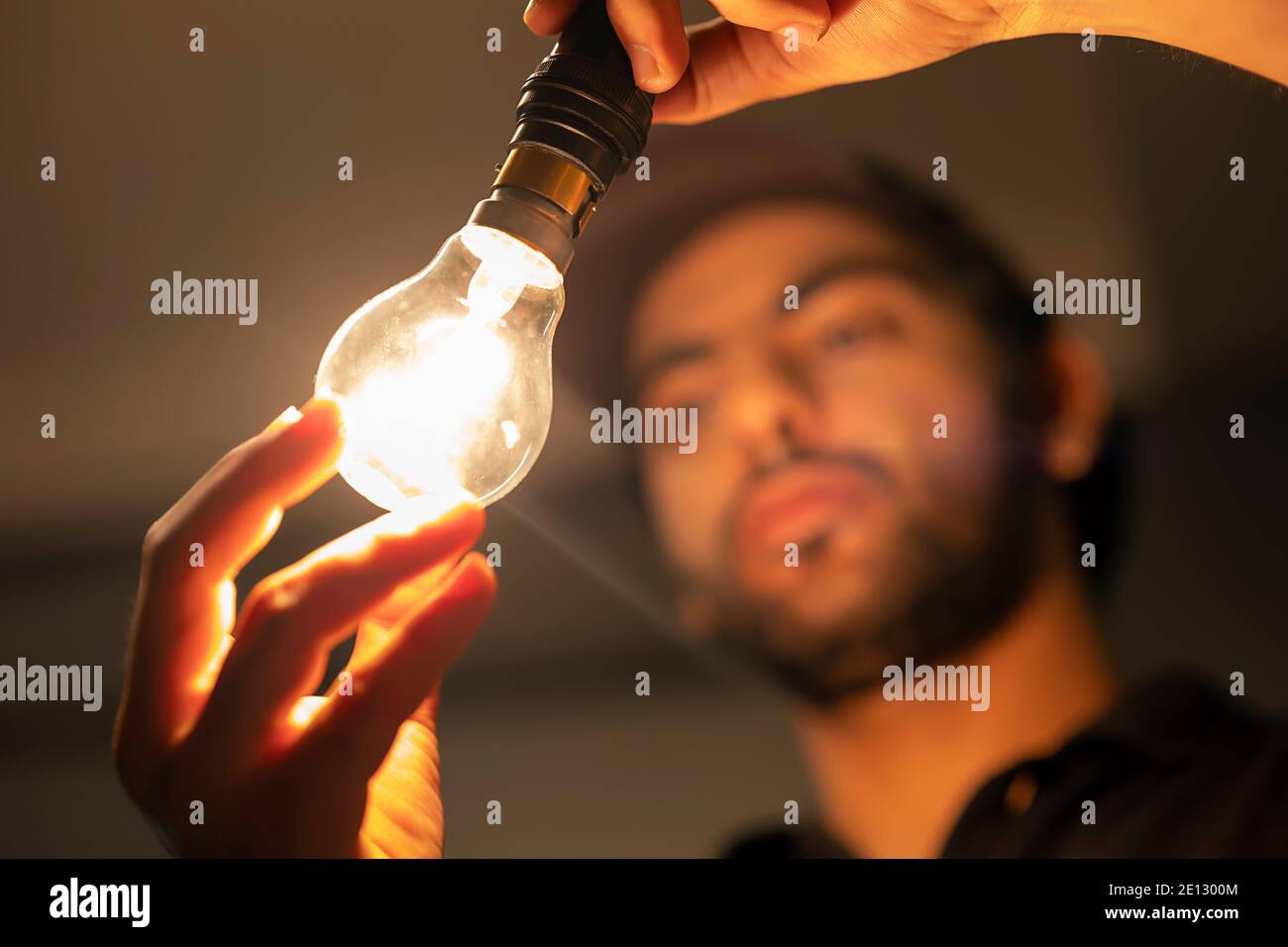 AN ELECTRICIAN HOLDING A WELL LIT ELECTRIC BULB Stock Photo