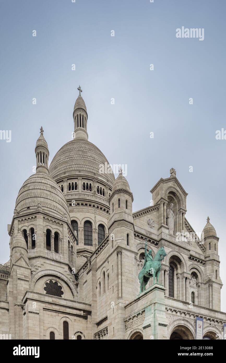 The basilicas of Sacre Coeur cathedral in Monmartre, with a sculpture of King Louis IX in the foreground. Stock Photo