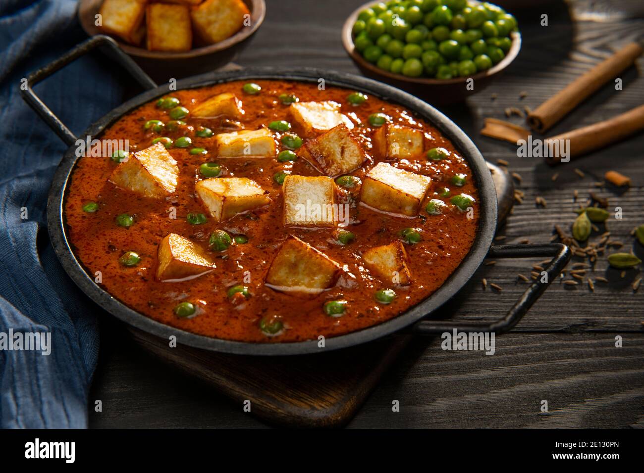 Mattar Paneer or cottage cheese with Peas. A vegetarian Indian delicacy, with raw peas and fried paneer (cottage cheese) in the background. Stock Photo