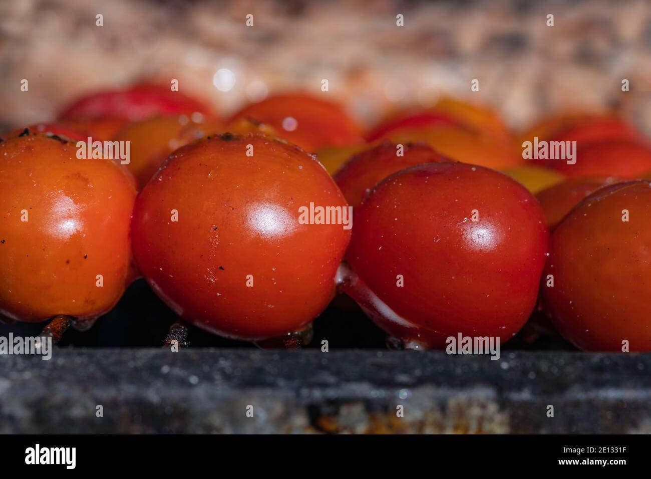 Cherry tomatoes and meat on skewers over an open fire close up