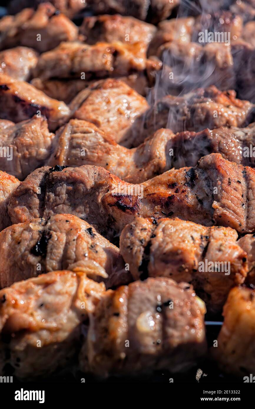Meat on skewers grilled over an open fire with smoke close up. Barbecue