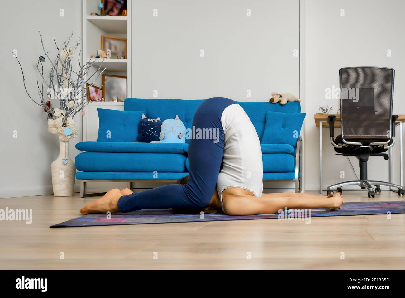 Young woman practicing yoga at home, doing plow pose Stock Photo - Alamy