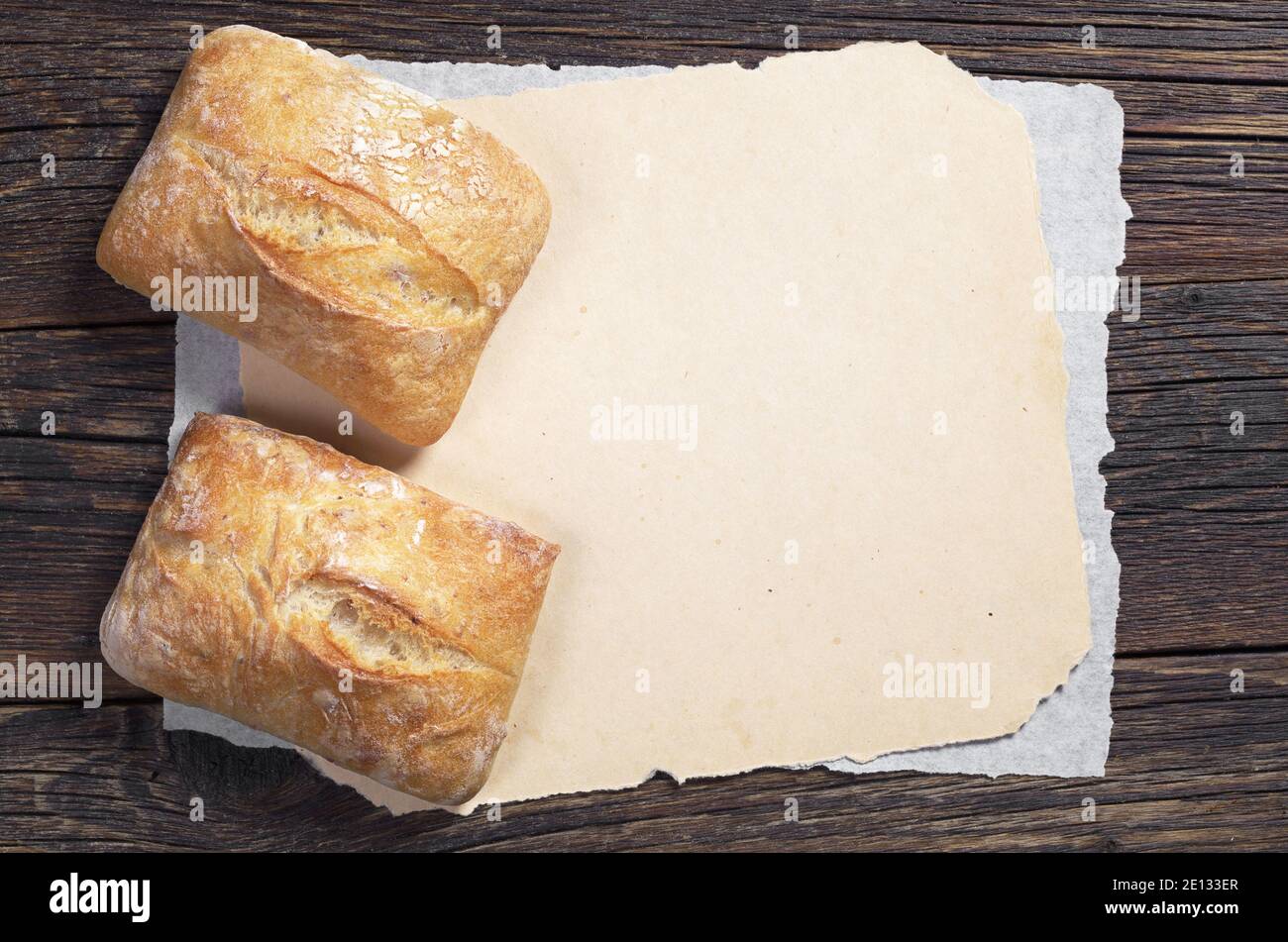 Fresh ciabatta bread on dark wooden table with blank paper, top view ...