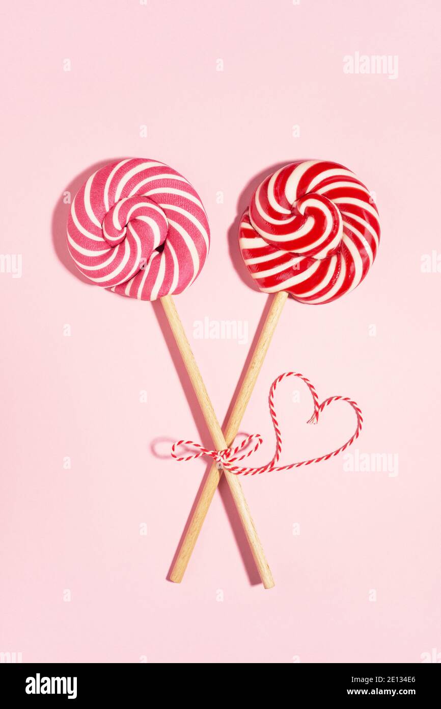 Two tied lollipop candys and red heart on Valentine's day, love concept. Stock Photo