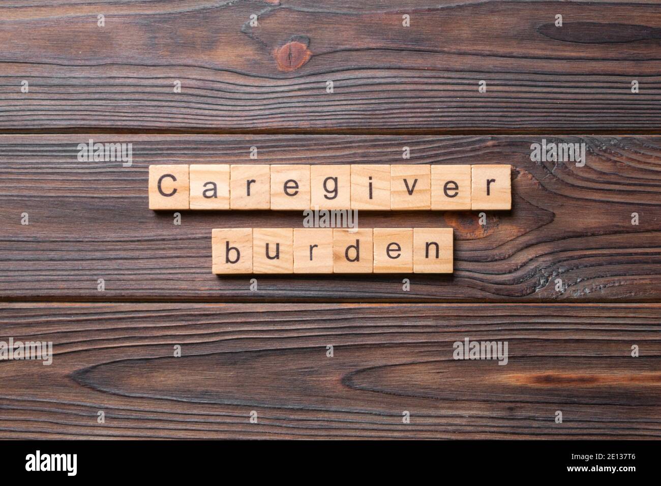 Caregiver burden word written on wood block. Caregiver burden text on