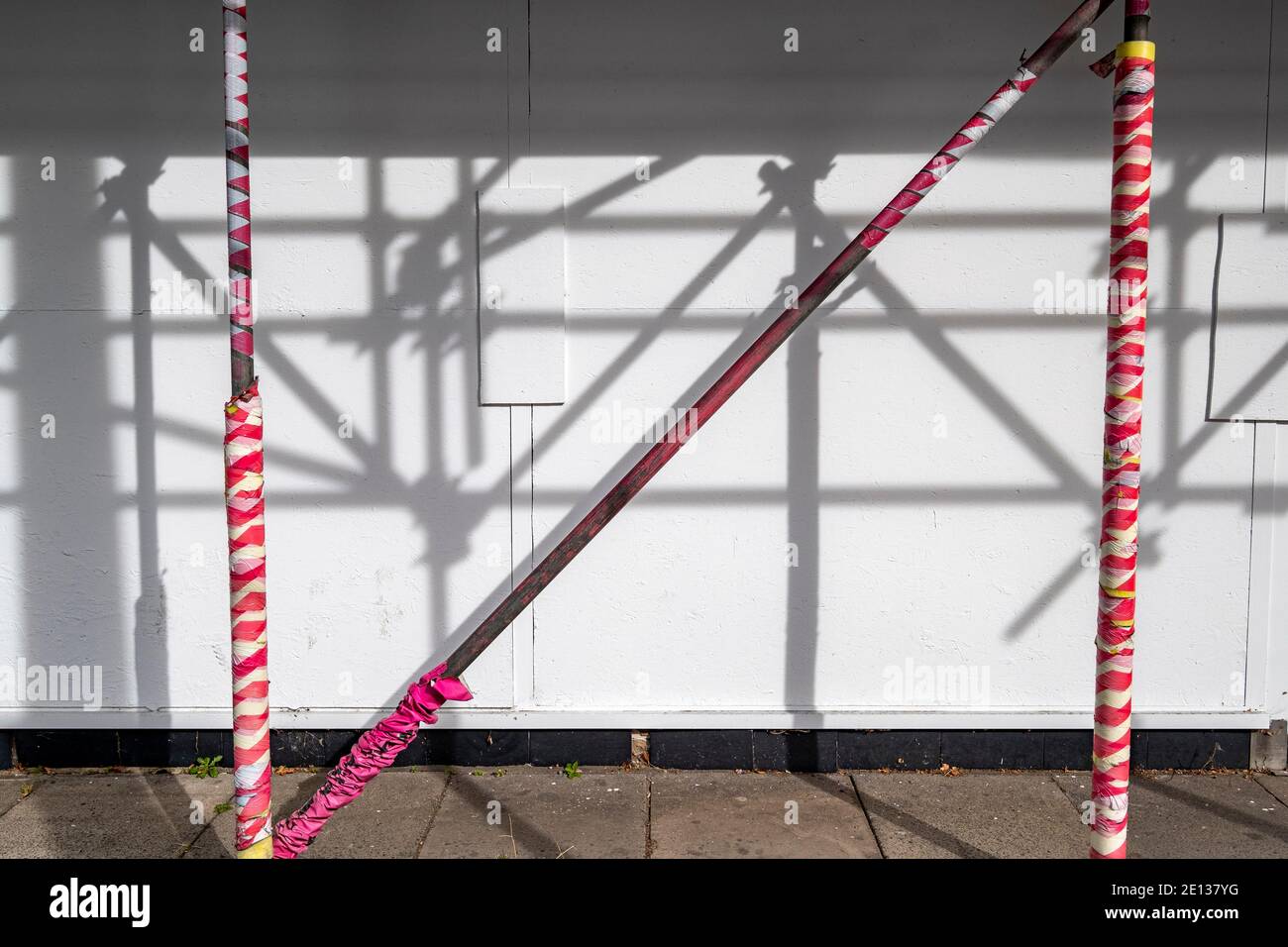 Shadow play of scaffolding on building site fence Stock Photo