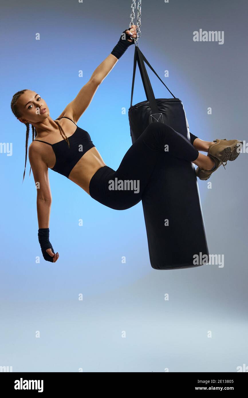 fit beautiful woman with boxing bandages and punching bag on studio background. full lenth Stock Photo