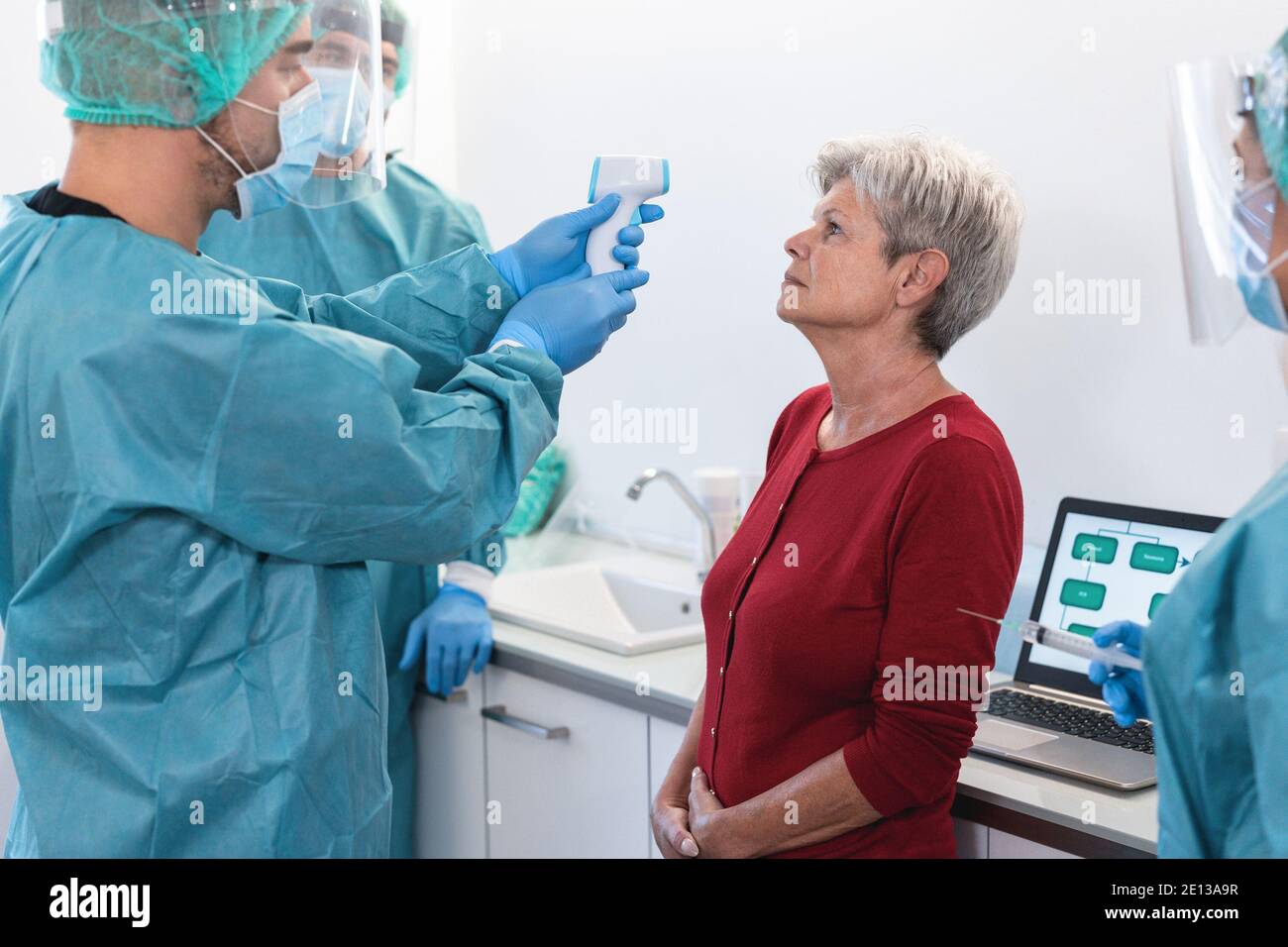 Doctor measuring fever to senior woman before coronavirus vaccination - Focus on patient Stock Photo