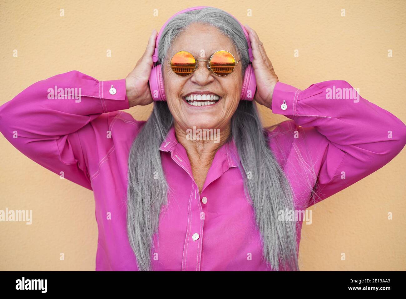 Happy senior woman listening to playlist music with headphones - Focus on face Stock Photo