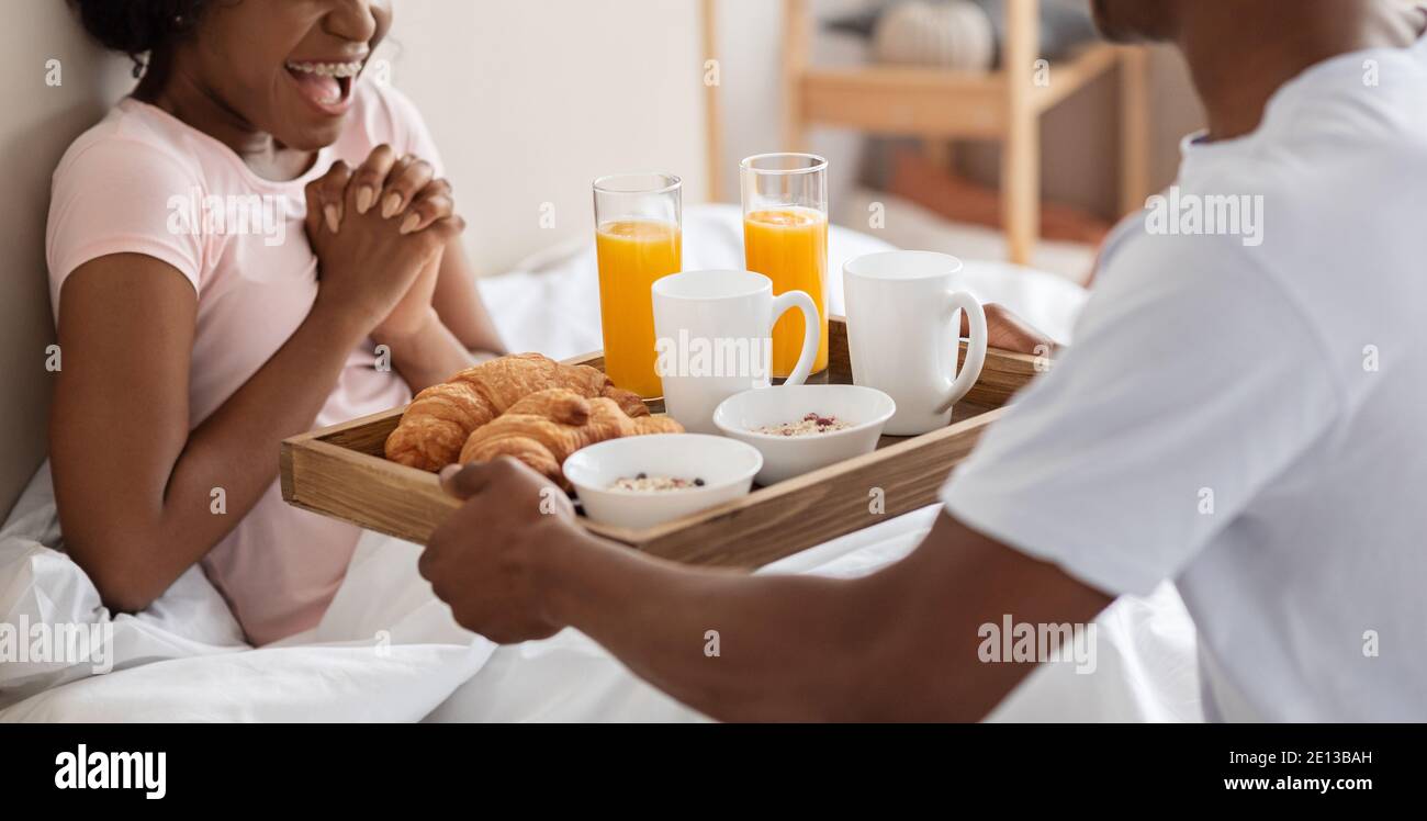 Cropped of african man bringing breakfast in bed for woman Stock Photo