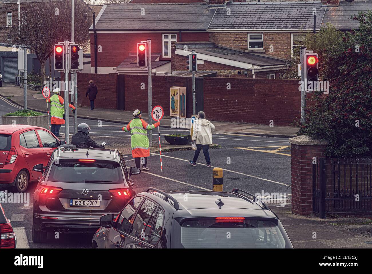 Everyday life. Crosswalk attendant helps people to cross road in heavy traffic. Dublin, Ireland. Stock Photo