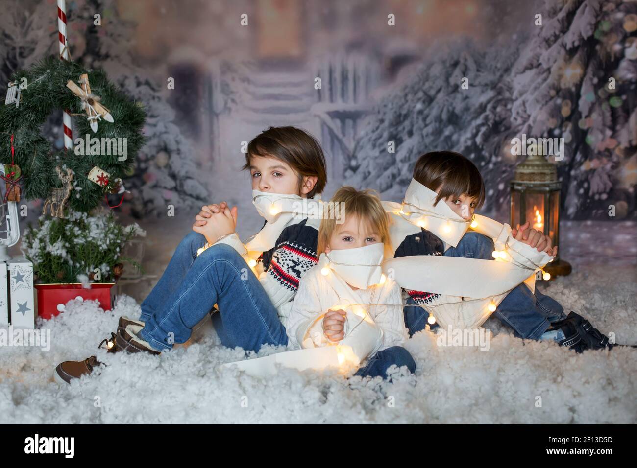 Children sitting in the snow wrapped in toilet paper and christmas