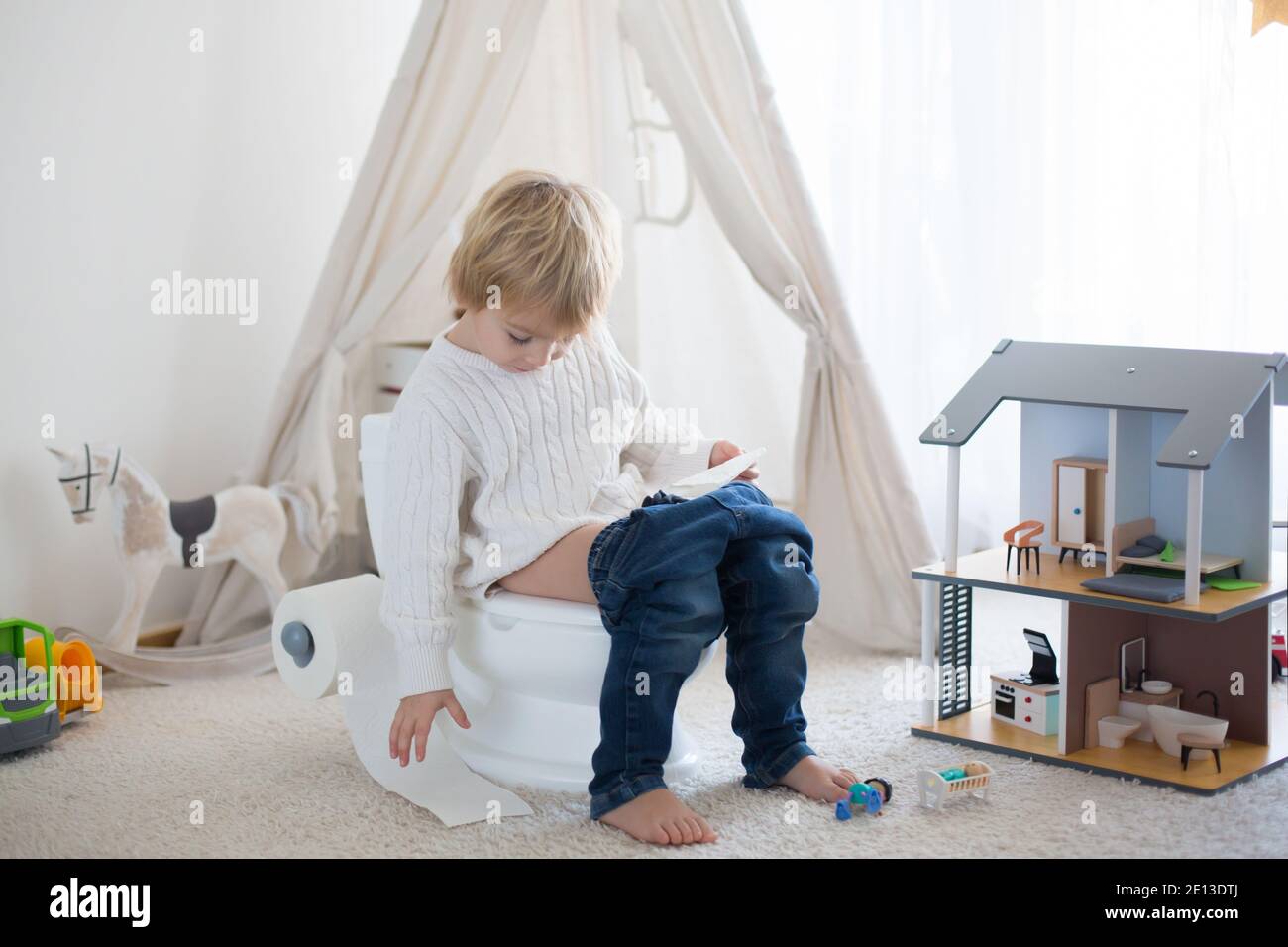 Cute toddler child, boy, sitting on a baby toilet potty, playing with