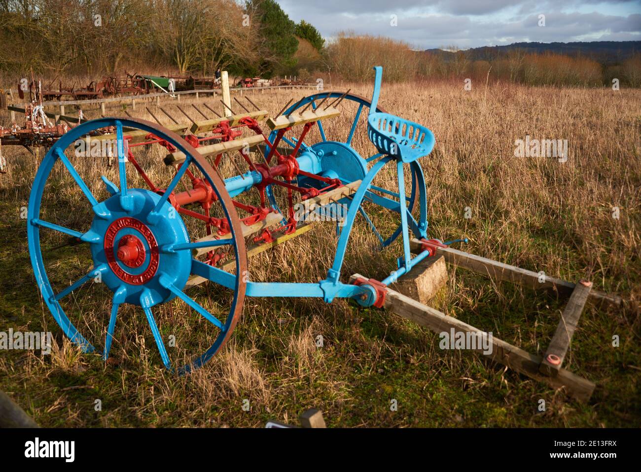 Old farming machinery in field, horse drawn tedder from 1800s painted
