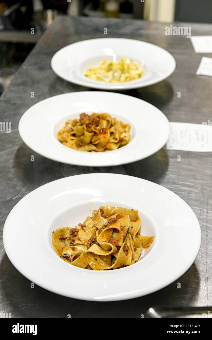 Bowls on a restaurant counter with Italian tagliatelli pasta topped with a ragu meat sauce ready for serving to customers Stock Photo