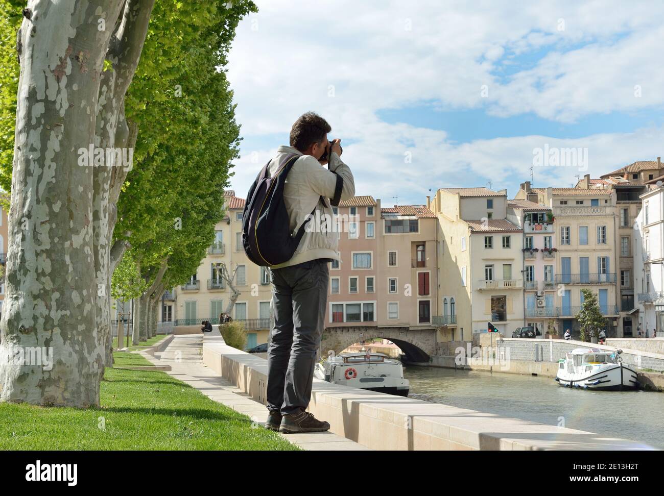 Photographer takes a picture near the green embankment of Narbonne with boats Stock Photo