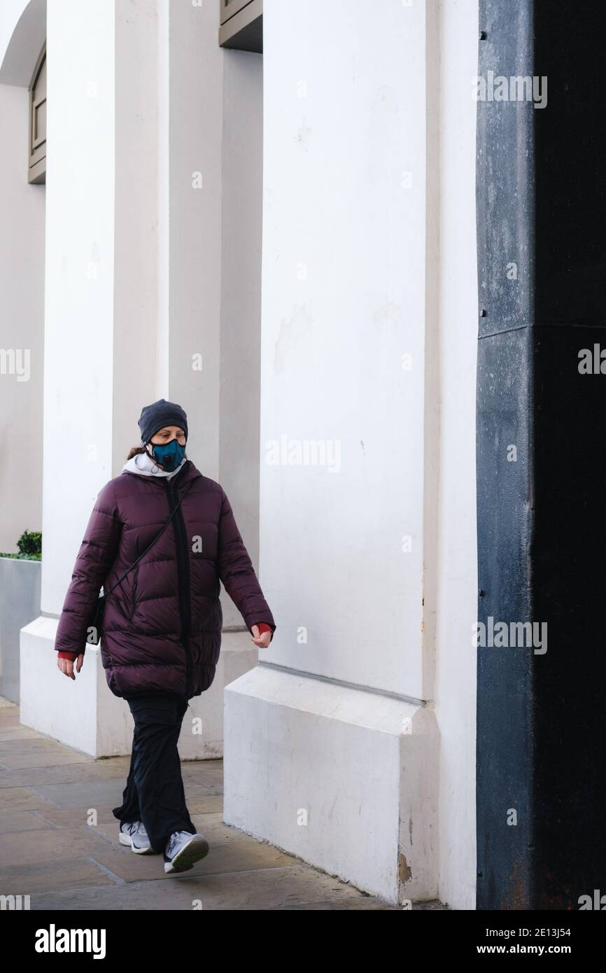London, UK - December 2020 :  woman with a face mask walks in London  during Tier 4 lockdown Stock Photo