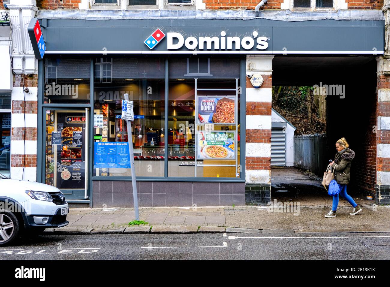 Epsom, London UK, January 03 2021, Young Woman Shopper Walking Past A Domino Pizza Take Away Shop Stock Photo