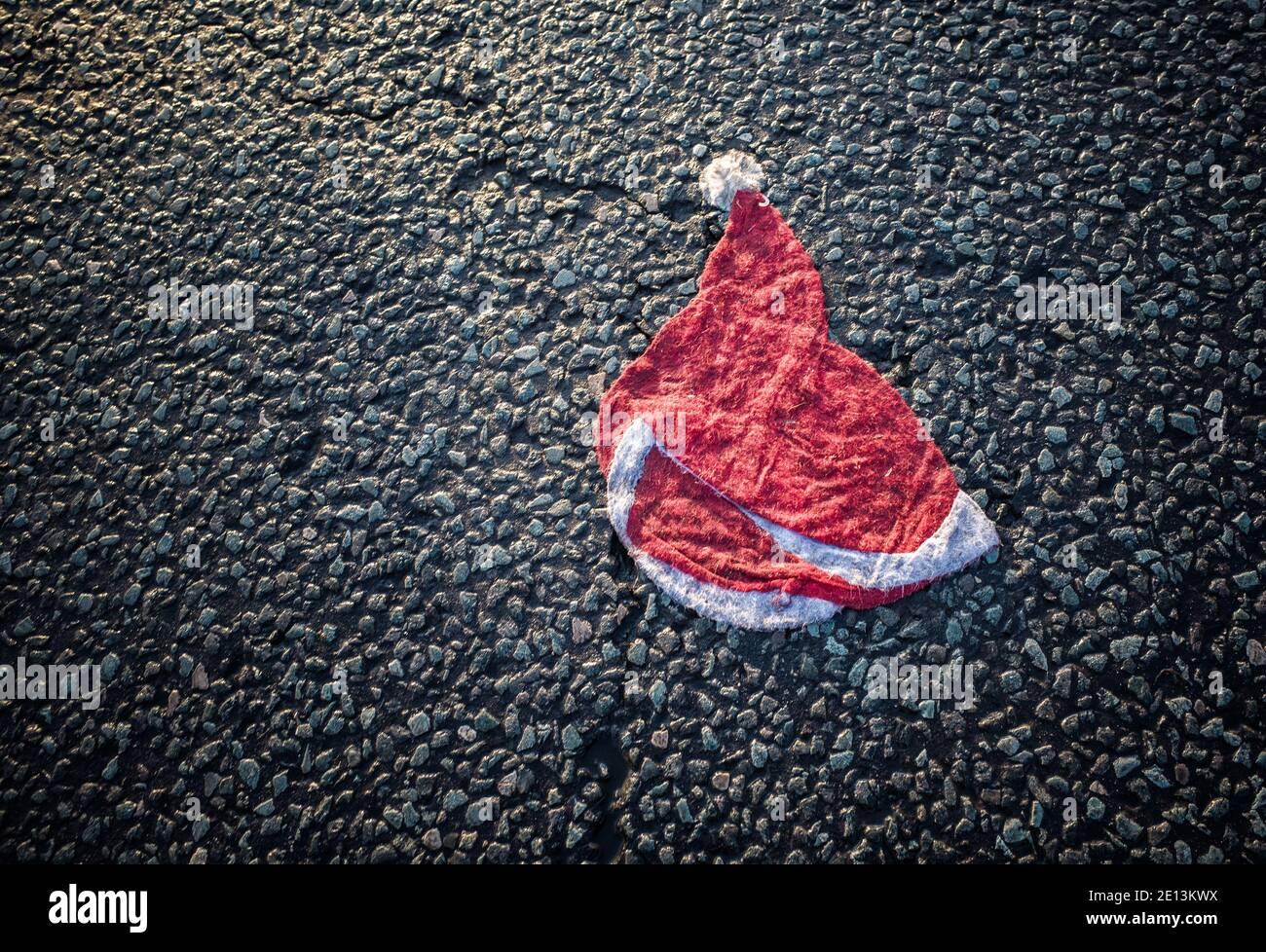 A squashed Santa hat with tyre marks in the middle of a road. Stock Photo