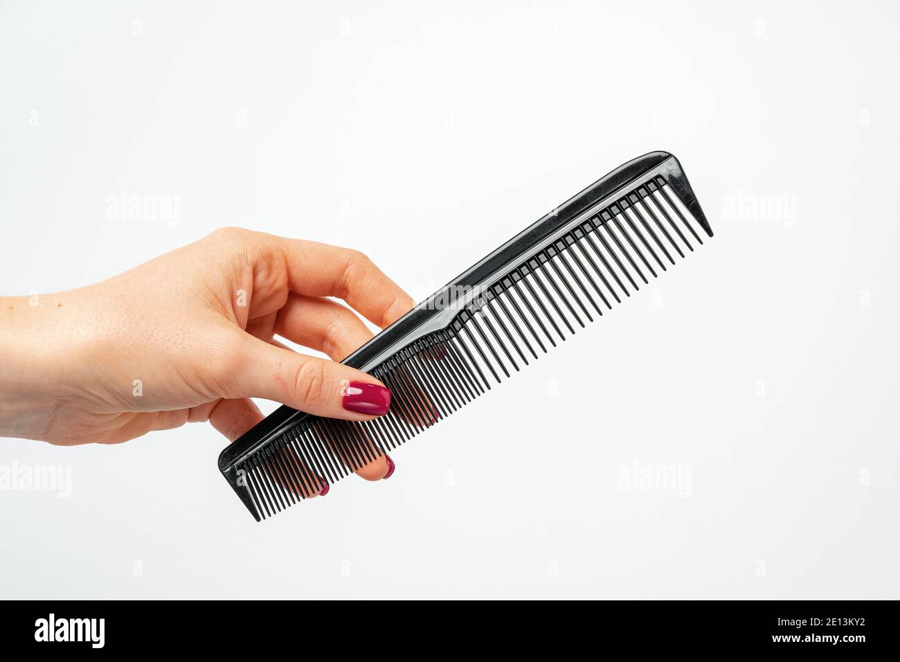 Female hand holding hair comb against white background Stock Photo - Alamy