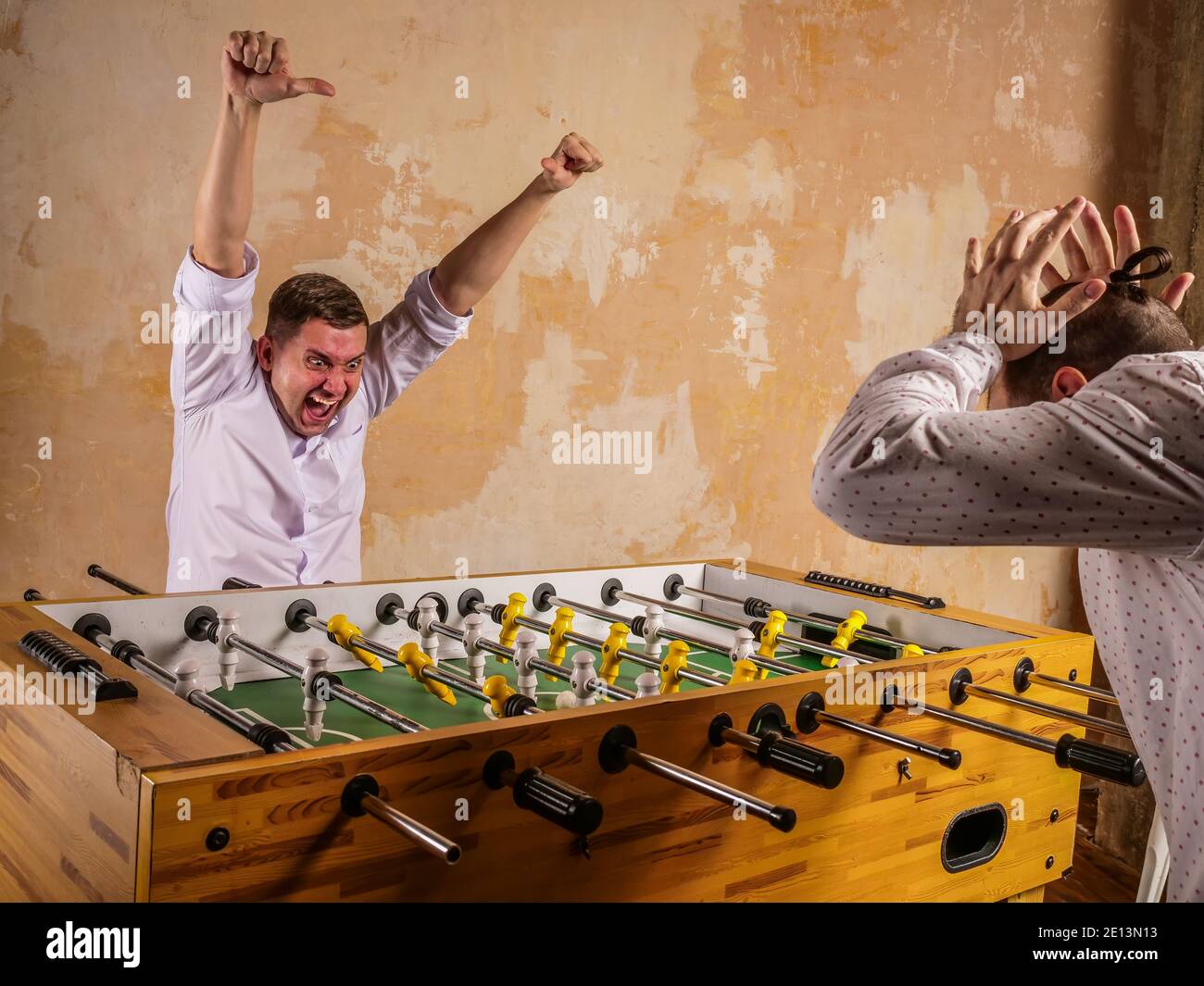 Colleagues are emotionally playing table football. Recreation and team building. Stock Photo