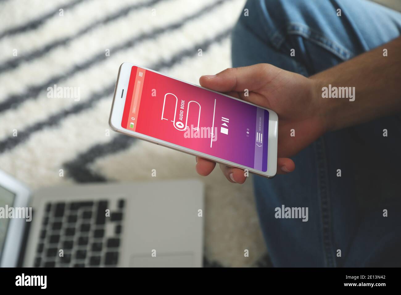 Man using audiobook application on modern smartphone at home, closeup Stock Photo