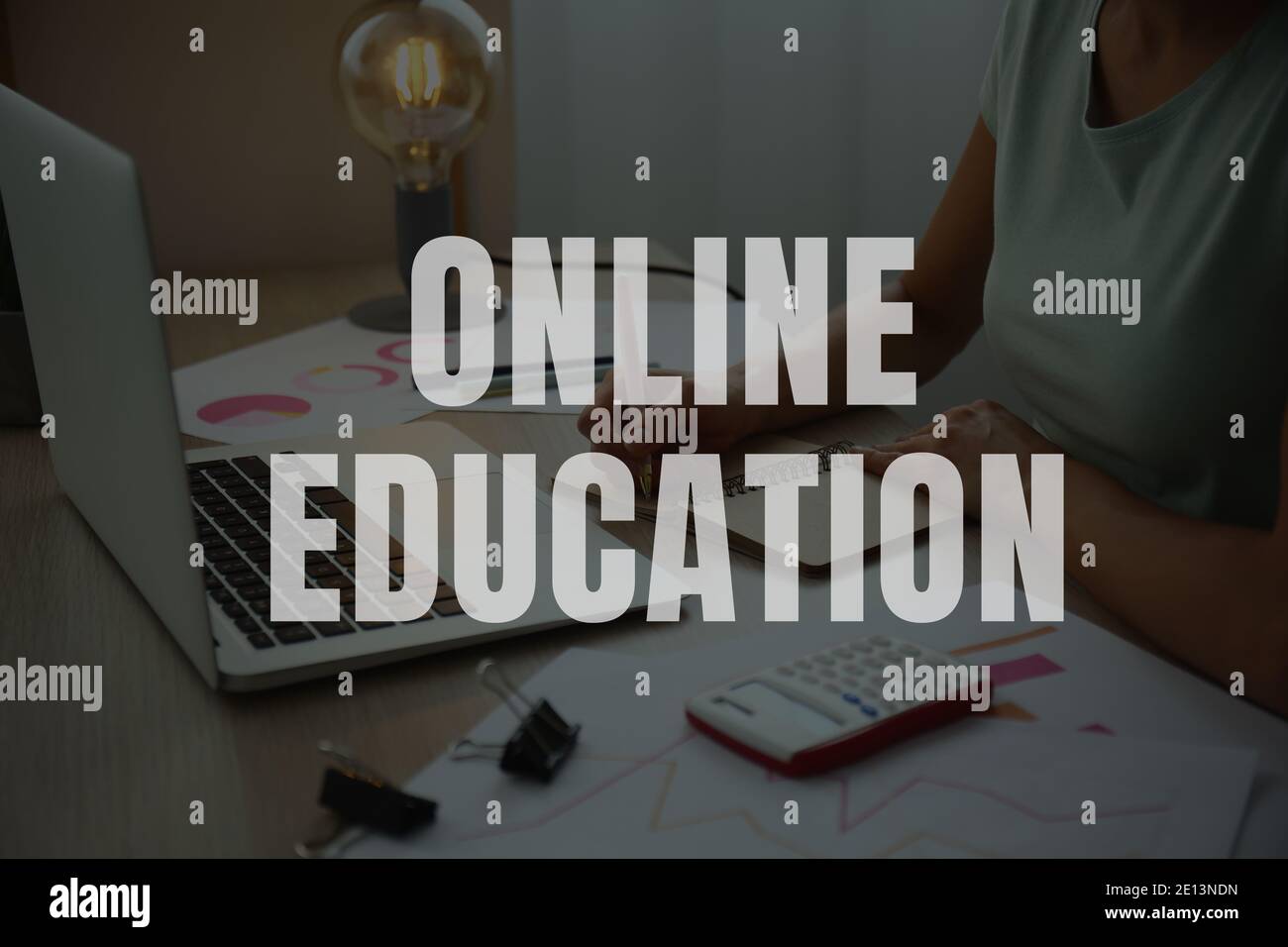 Text 'Online education' and young woman with laptop learning at home Stock Photo