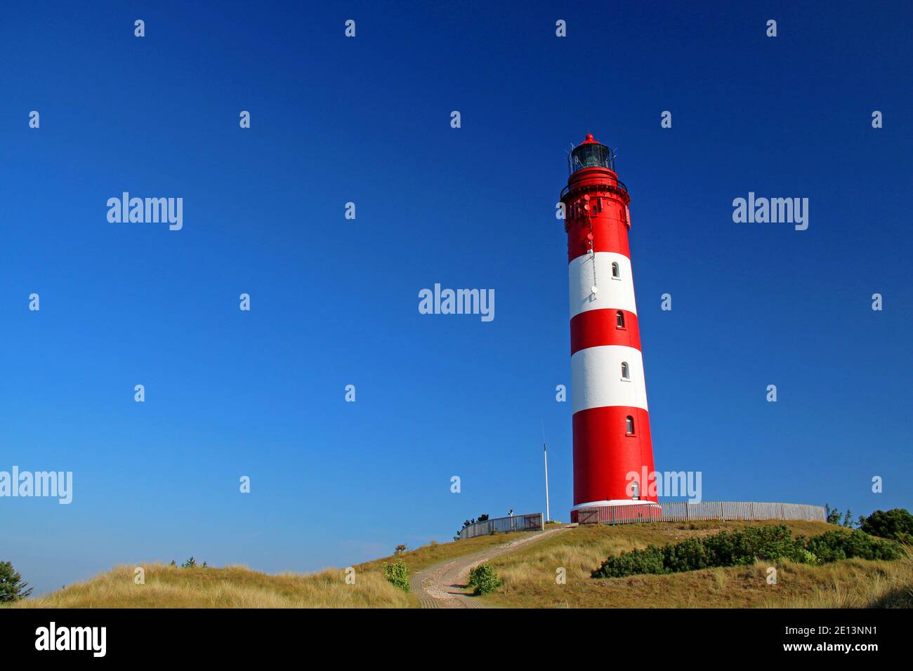 Red White Striped Lighthouse at the island of Amrum Germany on a sunny day with blue sky within the dunes Stock Photo