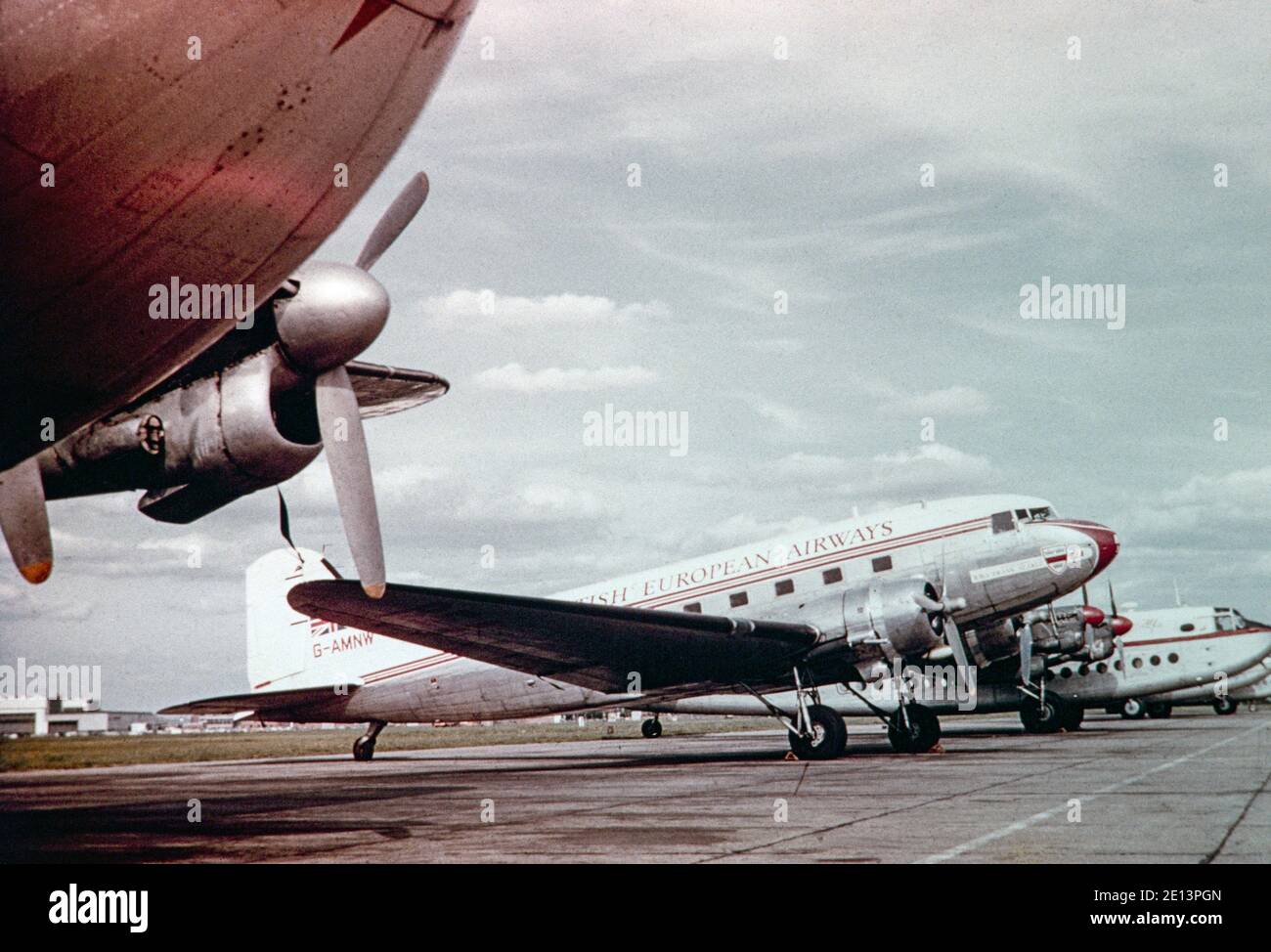 A vintage late 1950s colour photograph a British European Airways, BEA, Douglas DC-3, registration G-AMNW, parked at London Heathrow airport in England. A Dan Air Avro York can be seen behind it. Stock Photo