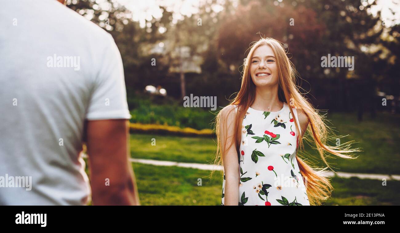 Gorgeous caucasian woman with red hair and freckles smile at her lover while playing in the park together Stock Photo