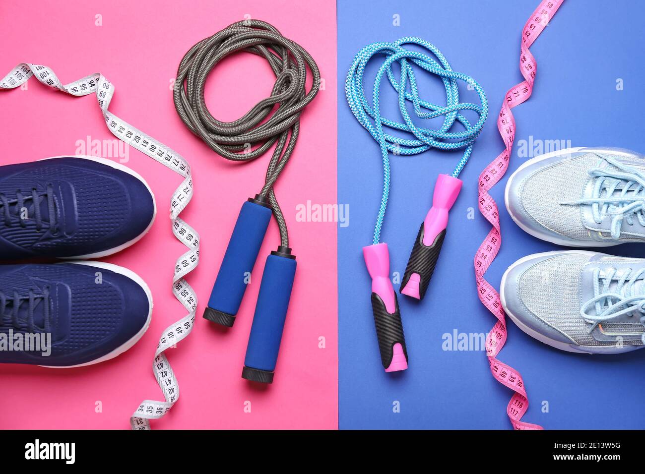 Male and female sportive shoes and jumping ropes on color background