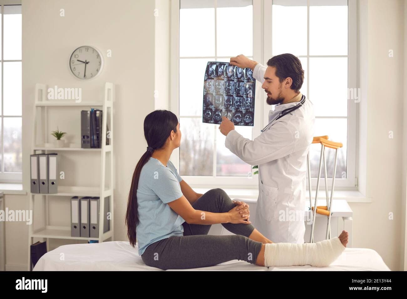 Trauma surgeon talking to woman and showing her X-ray image of her bone fracture Stock Photo